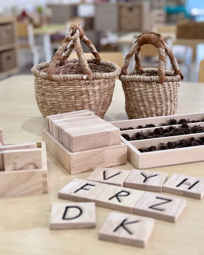 Wooden letter tiles and baskets set out for literacy