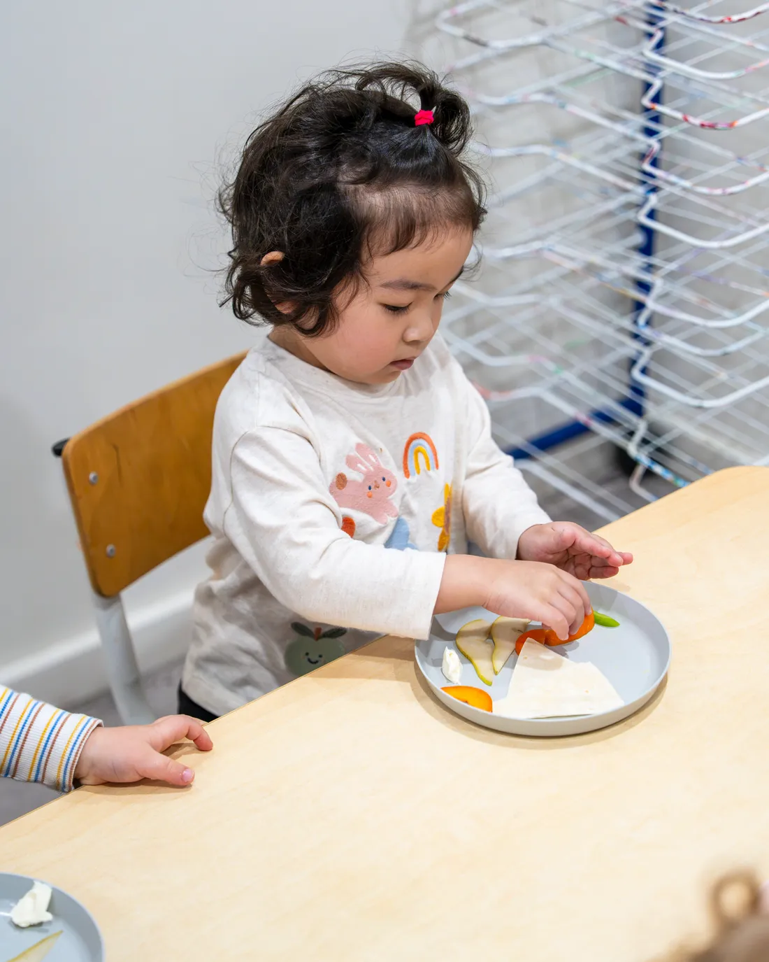 Toddler serving herself from a plate at Little Jungle Dundas