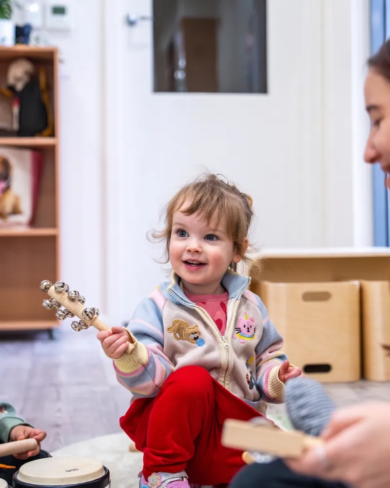 Toddler playing a tambourine in the Cuddle Cubs room, Little Jungle Dundas